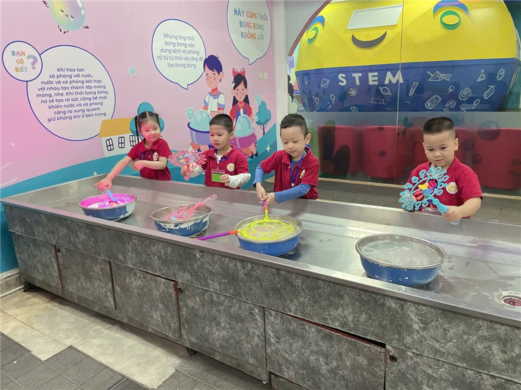 A group of kids in red uniforms mixing food

Description automatically generated