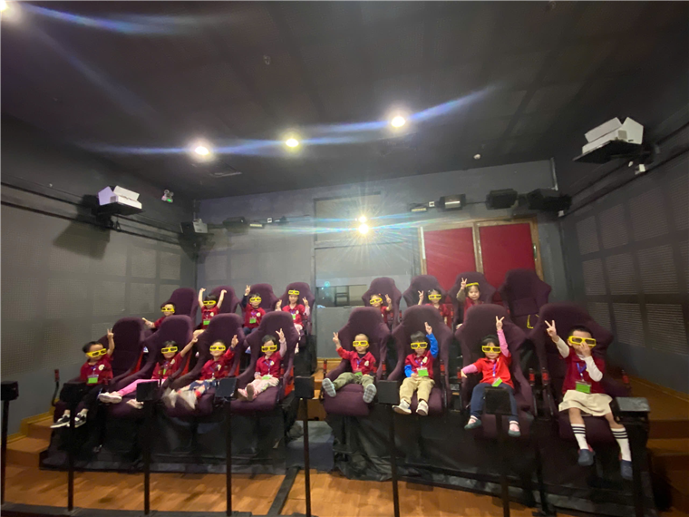 A group of children sitting on chairs in a theater

Description automatically generated
