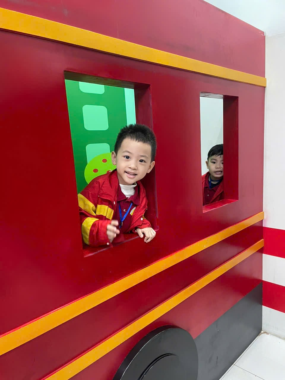 A child in a red and yellow vehicle

Description automatically generated