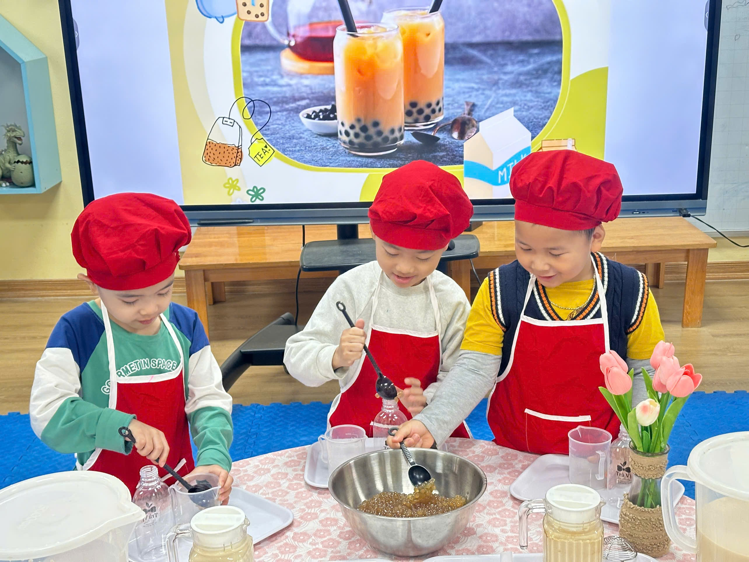 A group of kids wearing red hats and aprons
Description automatically generated