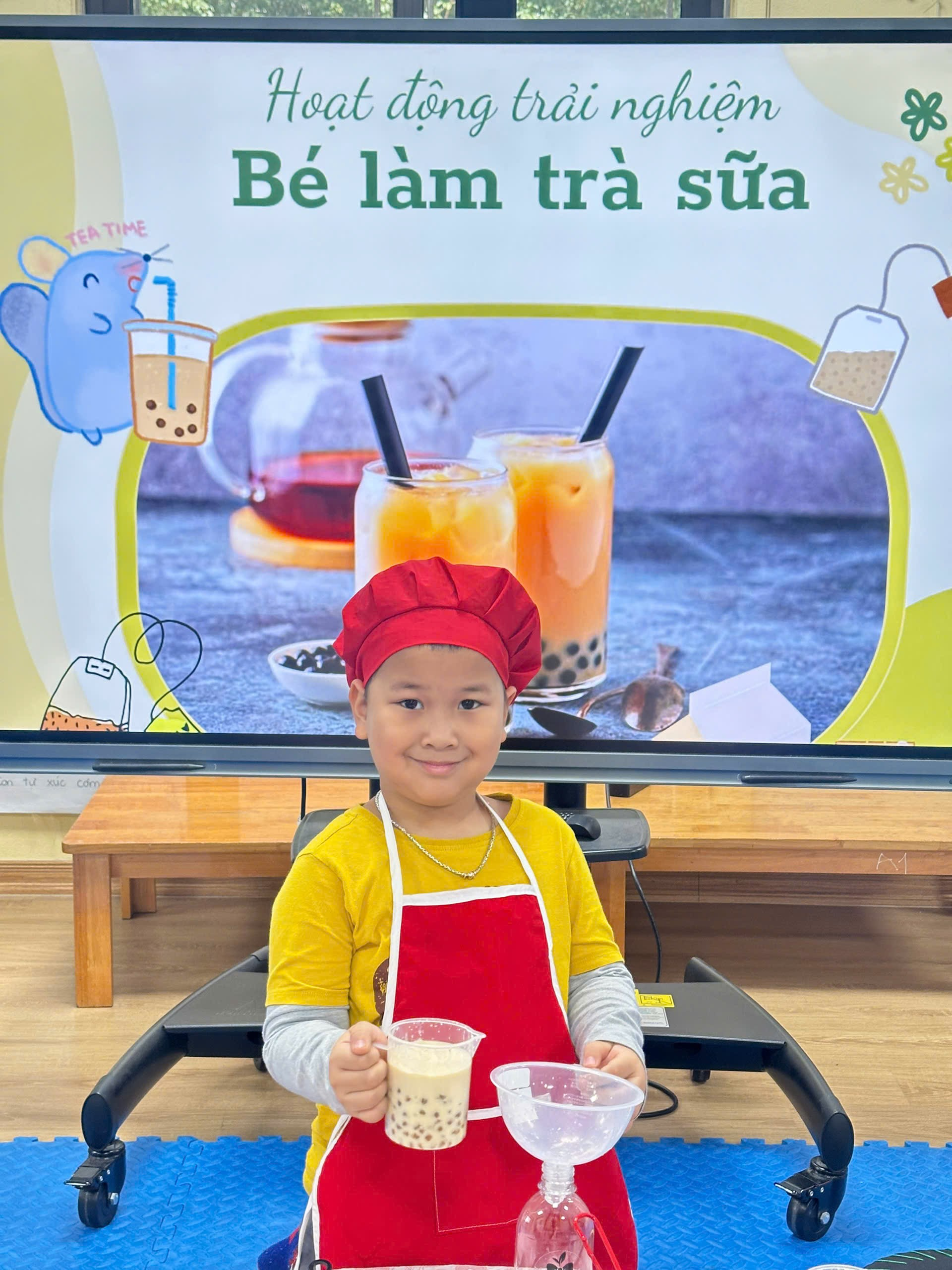 A child sitting in a chair holding a tray of milk
Description automatically generated