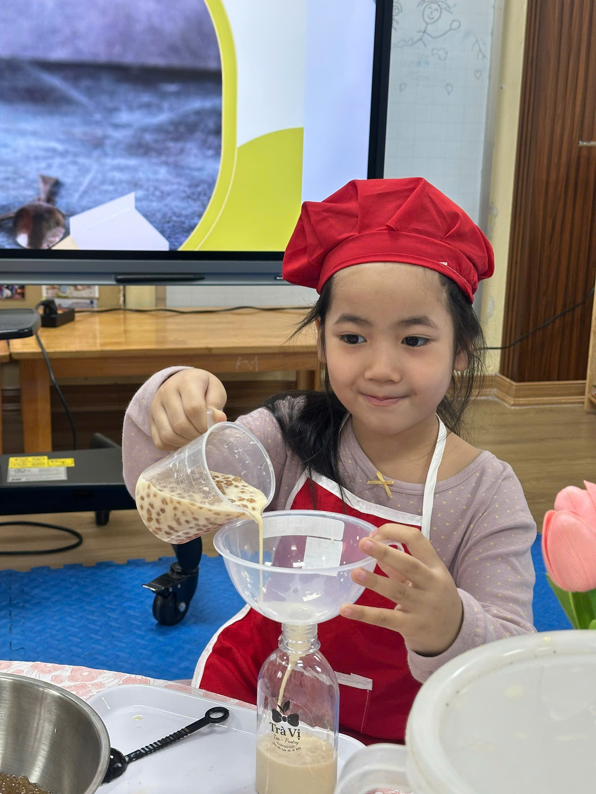 A child pouring a liquid into a cup
Description automatically generated