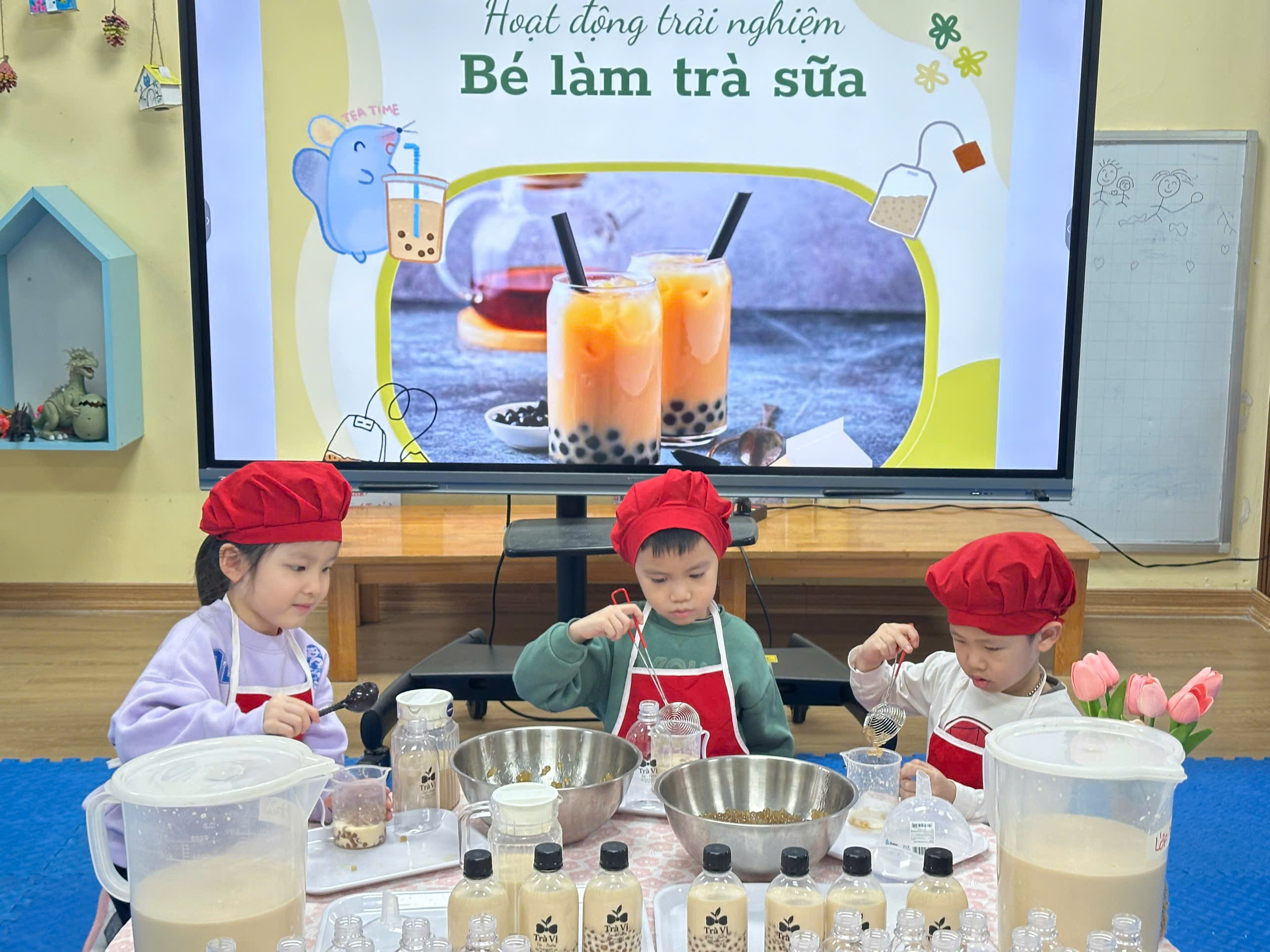 A group of kids in red hats and aprons in front of a screen
Description automatically generated