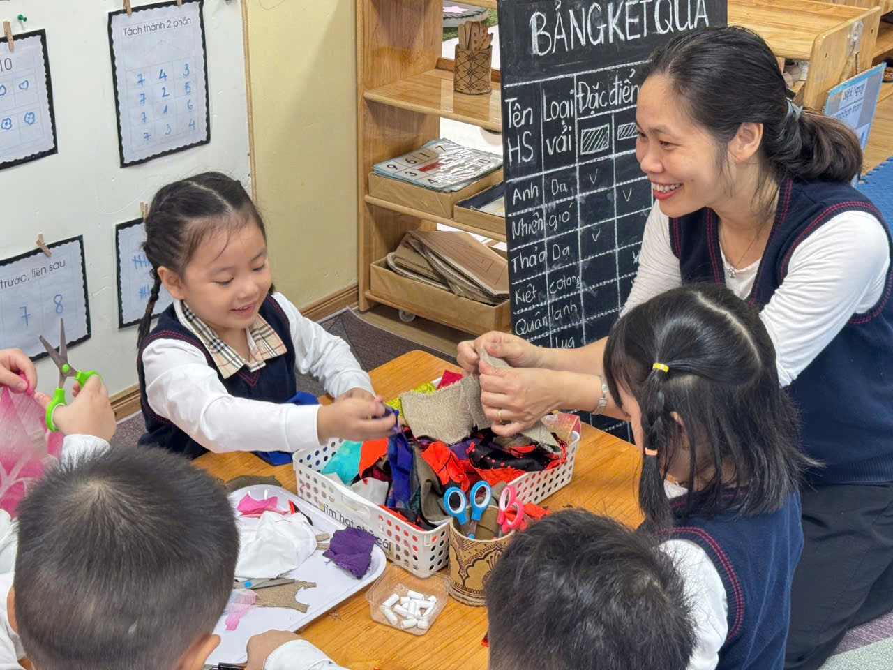 A teacher helping students with craft

Description automatically generated