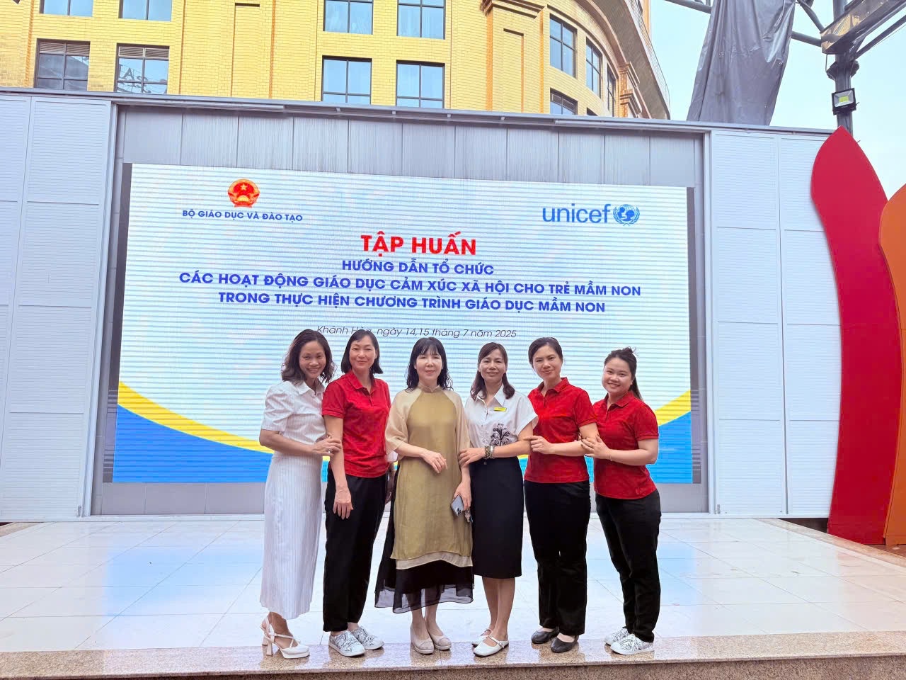 A group of women standing in front of a sign

AI-generated content may be incorrect.