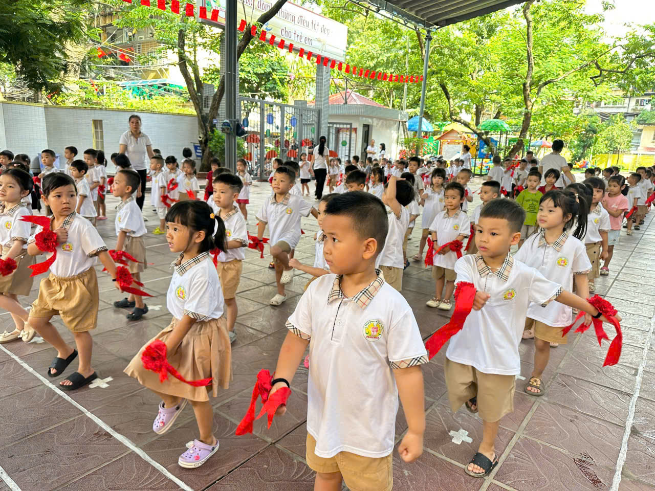 A group of children running with red ribbons

Description automatically generated