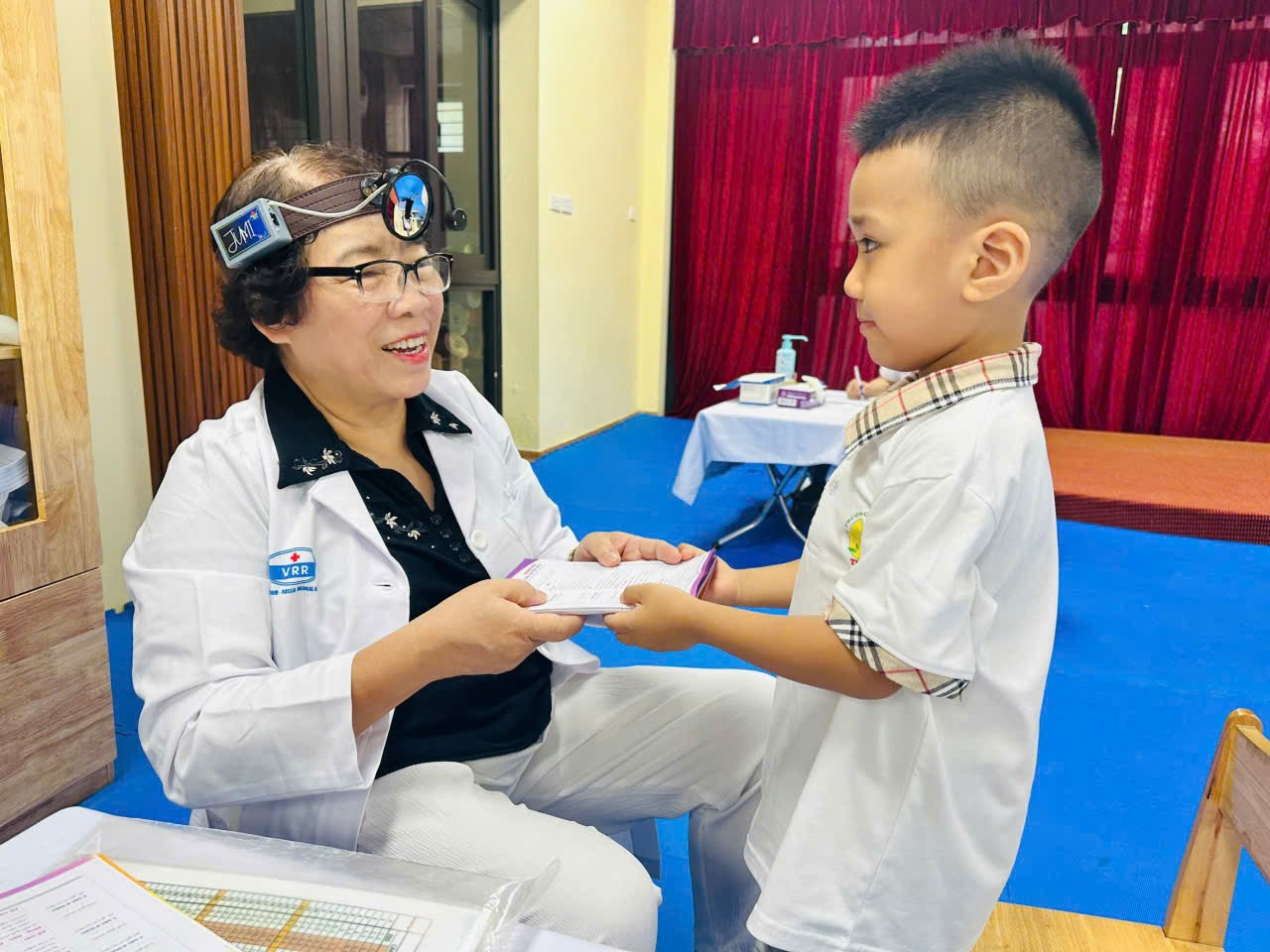A person in white coat holding a child's head

Description automatically generated