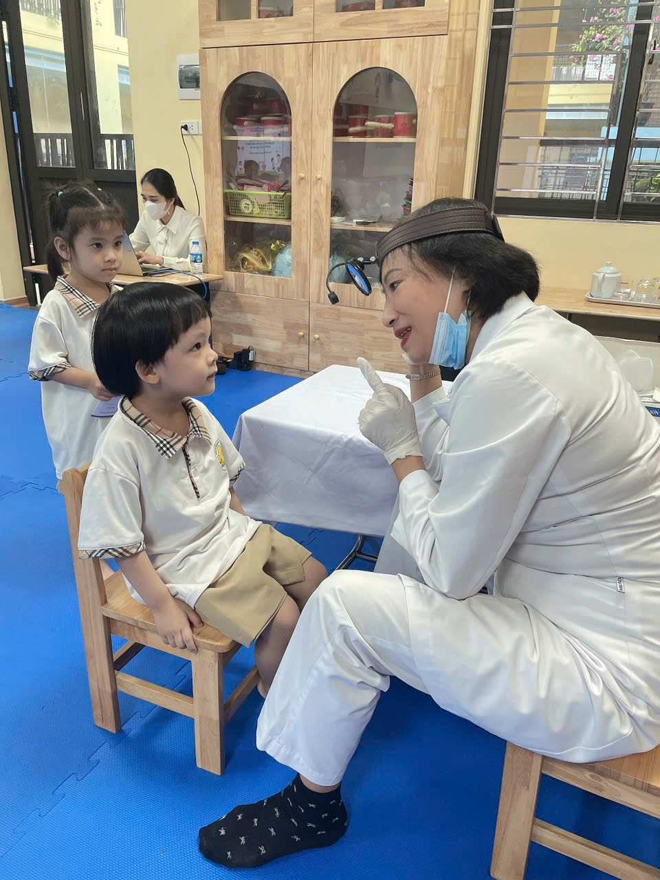 A person in white coat sitting in a chair with a child in a classroom

AI-generated content may be incorrect.