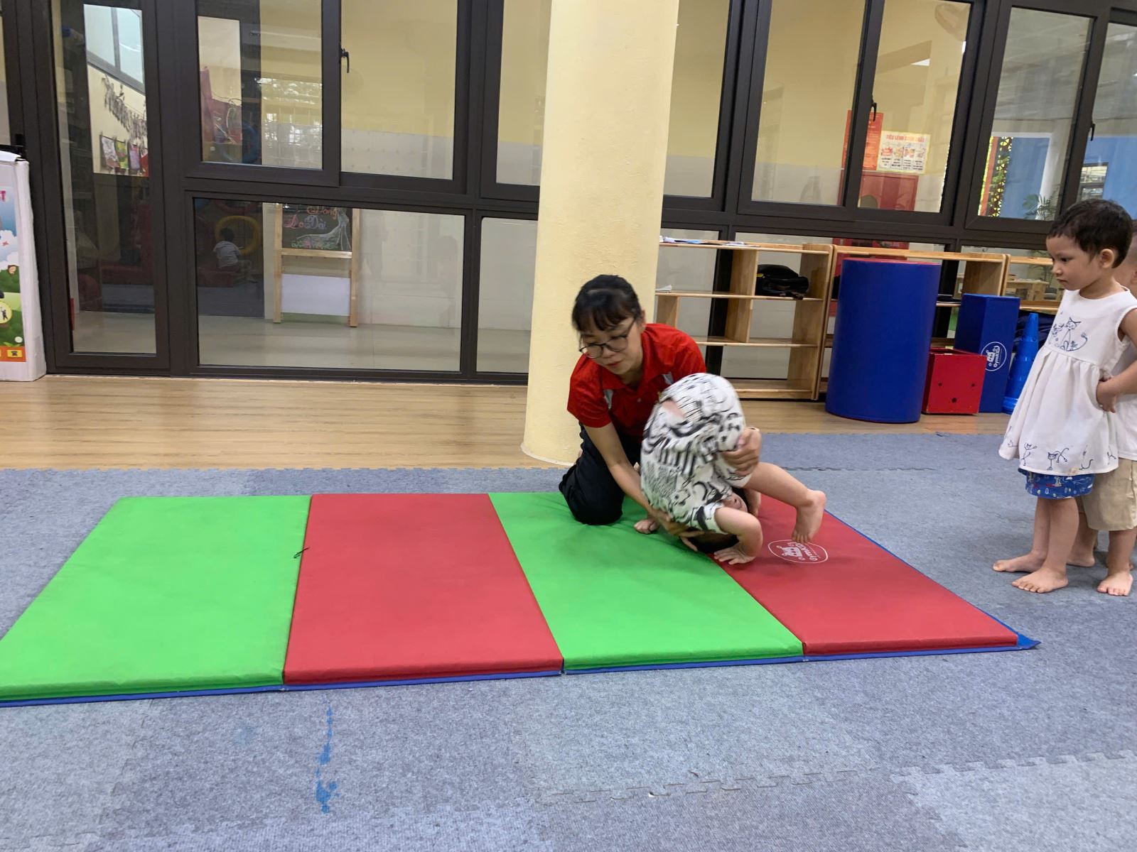 Giáo viên đang hỗ trợ các bé tập động tác lộn...