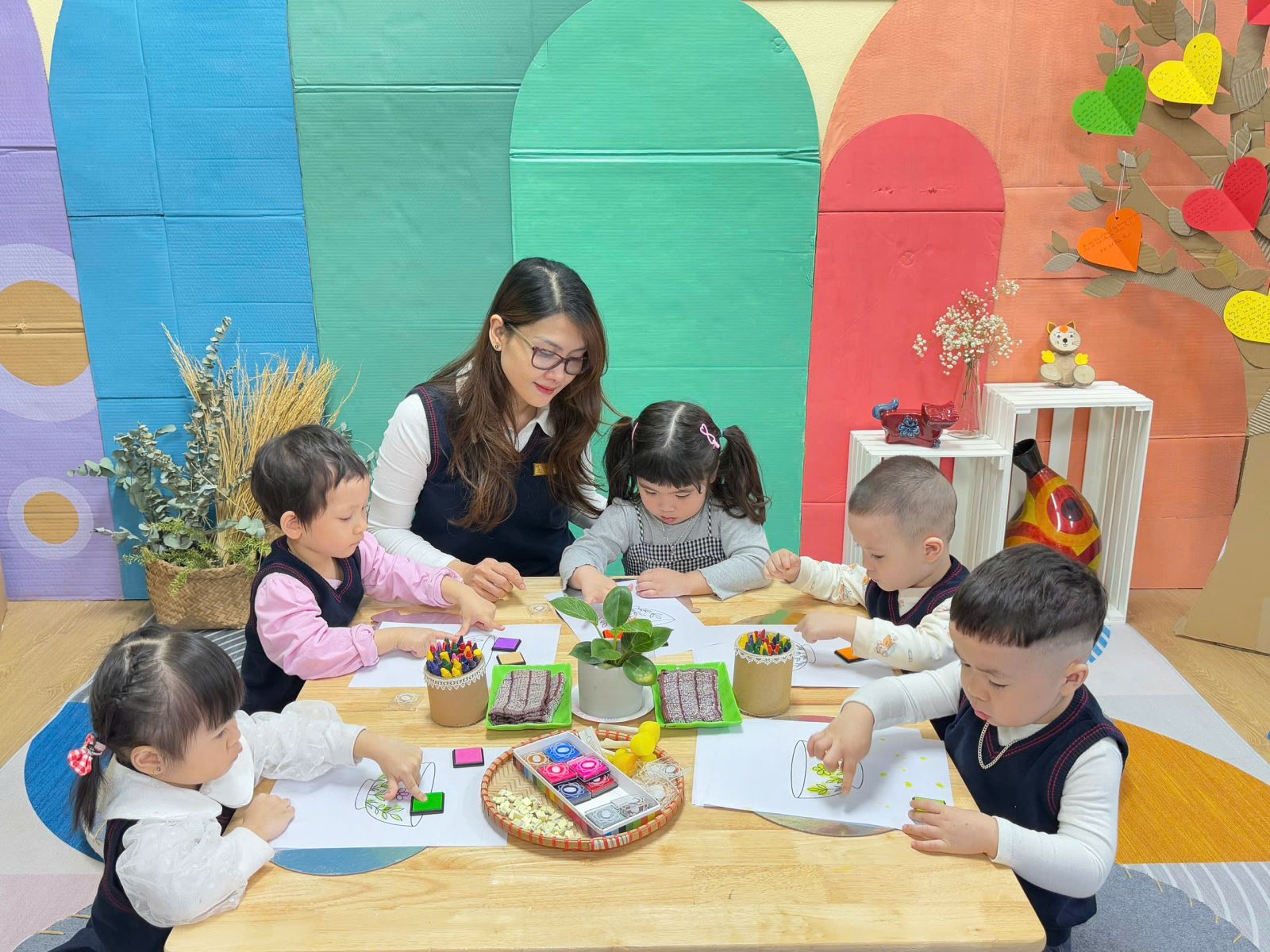 Các bé đang chơi tại góc nghệ thuật với hoạt động "Trang trí đồ dùng ăn uống trong gia đình"