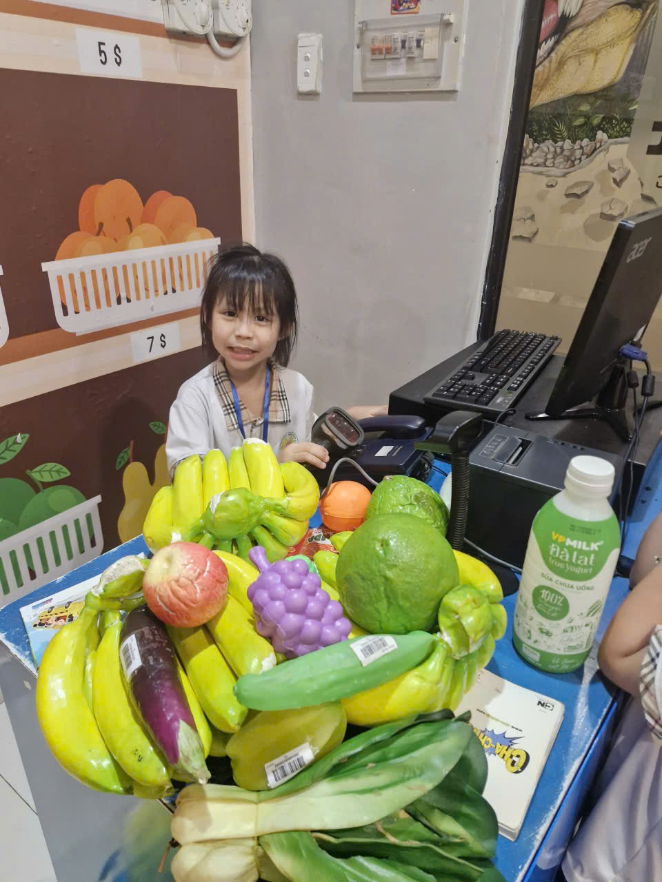 A child standing behind a table full of fruits

Description automatically generated
