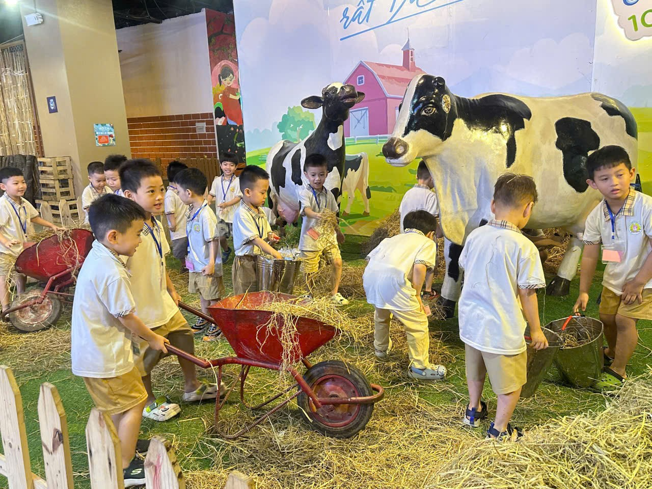 A group of children in a room with cows and cows

Description automatically generated