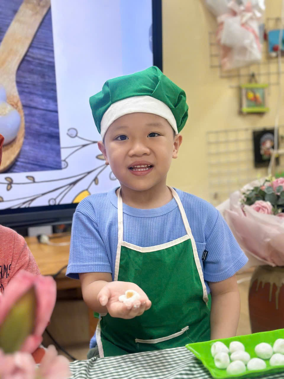 A young child wearing a chef hat and apron

Description automatically generated